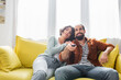 © LIGHTFIELD STUDIOS - happy hispanic couple watching tv on sofa at home