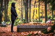 Sad woman is mourning for dead person at grave in cemetery. Lonely mourner in autumn graveyard