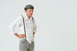Fototapeta Lawenda - Portrait of hipster man dressed in white shirt and grey jeans and wool cap isolated on white background. Copy space at right side.