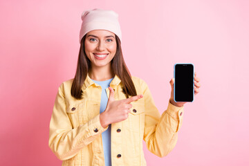 Sticker - Portrait of attractive lady point finger phone screen empty space wear cap isolated on pink color background