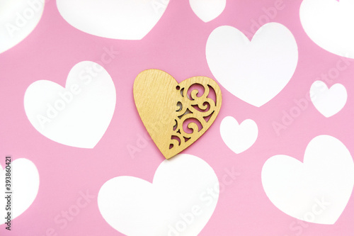 carved wooden heart on pink background with hand drawn white hearts,  Concept of love and romance. Beautiful background for Valentines Day. Space for copy space and lettering. Minimal concept