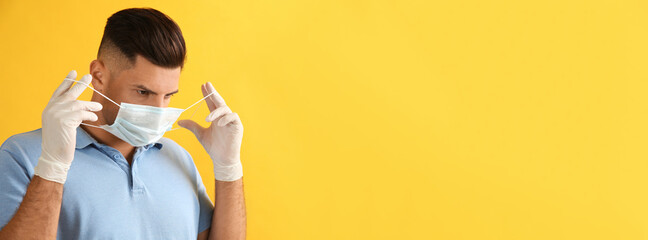 Sticker - Man in medical gloves putting on protective face mask against yellow background. Space for text