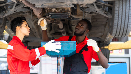 Sticker - Black Male And Female trainee Mechanics Working Underneath Car Together Car maintenance and auto service garage.