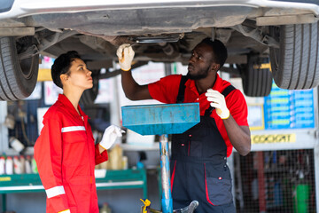 Sticker - Black Male And Female trainee Mechanics Working Underneath Car Together Car maintenance and auto service garage.