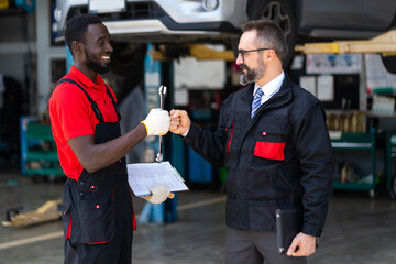 Wall Mural - Portrait Auto mechanic with wrench in hand. stranglehold. Closeup car repair black man hand and caucasian man manager or owner.