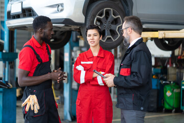 Team of mechanics discussing at the repair garage. Professional Expertise mechanic team working in automobile repair garage.