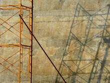 Yellow Scaffolding With Shadow On Brown Concrete Wall Background