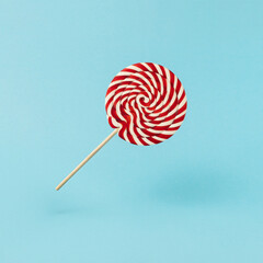 Colorful lolipop on blue background, wooden stick, red and white spiral, childhood sweets, Christmas concept