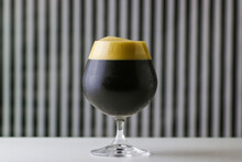 Glass Of Dark Craft Beer With Creamy Head 