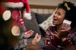 © luckybusiness - afro-american female shaking  present that she got for christmas near her ear, listening, trying to guess what it is inside the box