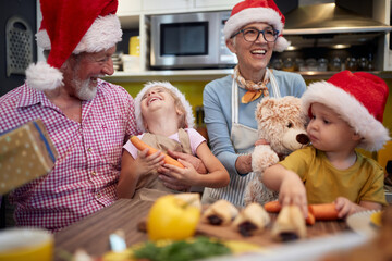 Grandparent with grandchildren having fun at preparing Xmas meal together in the kitchen. Christmas, family, together