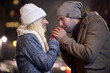A young couple warming up in a cold night walk in the city. Love, together, walk, snow, city