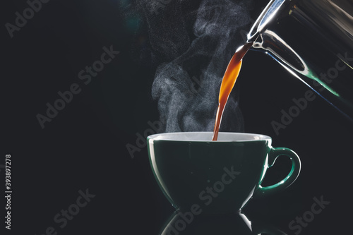 Fotomural Pouring of hot coffee in cup on dark background