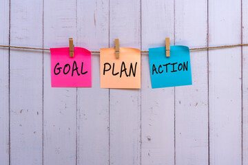 Wall Mural - Goal, plan, action text on colorful paper note hanging with clothespin, wood rustic background