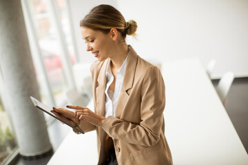 Wall Mural - Happy woman manager holding digital tablet and standing in modern office