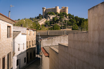 View of medieval castle on the top of the hill from the streets of the village of Belmonte in daylight, Cuenca, Spain