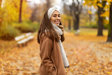 Wall Mural - portrait of smiling young woman in a park in autumn