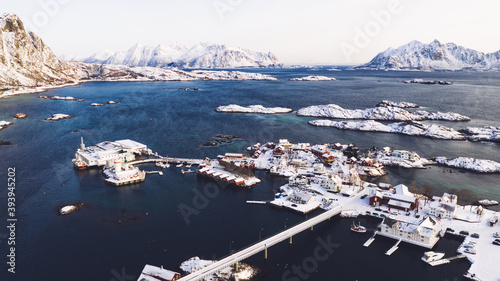 Breathtaking bird's eye view of Lofoten fishing village with red Traditional Norwegian houses. Aerial view from drone of panoramic island landscape with small city infrastructure between fjords