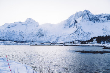 High nordic fjord landscape and cold nature over water in sea scenic destination on winter,beautiful calm white mountain near lake on coast in arctic climate location