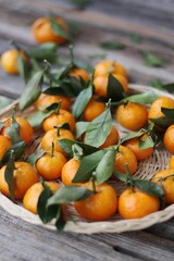 Sticker - Juicy tangerines with green leaves on a wooden table 