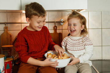 Wall Mural - Christmas. Adorable little girl and boy eating Christmas cookies and drinking hot tea in New Year's decorations. Winter holidays.