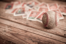 Old, Used, And Dirty Baseball With Sports Cards Blurred In Background