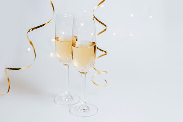 Wall Mural - Two glasses of champagne with lights and ribbons on a white background holiday