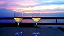 Wineglass On Table By Sea Against Sky During Sunset