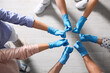 © New Africa - Group of people in blue medical gloves showing thumbs up indoors, top view