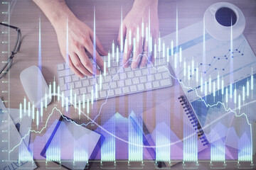 Multi exposure of man's hands typing over computer keyboard and forex graph hologram drawing. Top view. Financial markets concept.