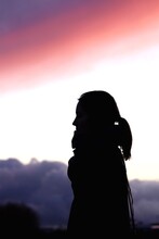 Side View Of Silhouette Woman Standing Against Sky During Sunset