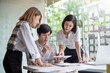 © amnaj - Group of young asian modern people in smart casual wear having a brainstorm meeting. Group of young asian business people discussing in the meeting.