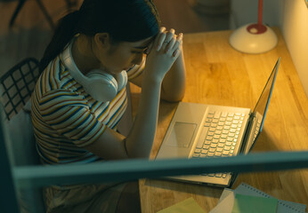 Tired Asian woman trying to get work done at night