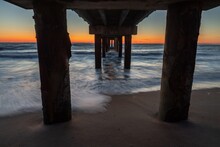 Below View Of Pier At Beach Against Sky During Sunset