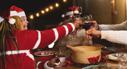 Wall Mural - Happy multiracial senior friends toasting with red wine glasses during Christmas holidays dinner celebration on patio house party