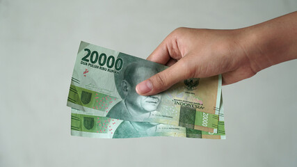 Indonesian rupiah currency, 20,000 rupiah, is held by women's hands