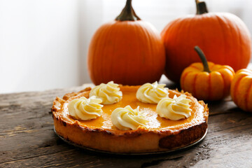 Wall Mural - Traditional thanksgiving food on wooden table. Orange delicious homemade pumpkin pie with crust and decorative items. Thanksgiving table setting concept.Top view, close up, copy space, background.