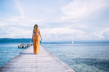 Young Blonde In Yellow Dress Walking On Pier