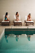 © Brkati Krokodil/Stocksy - Three Girlfriends Enjoying Together On Sunbeds By The Indoor Pool
