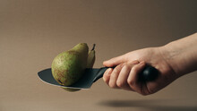 Person Cutting A Pear With Kitchen Knife