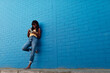 © JAVIER PARDINA/Stocksy - Woman using phone on a blue backgound.