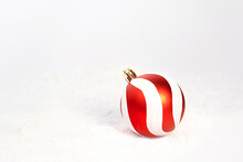 Red White Christmas Decoration Bauble On White Snow Background.