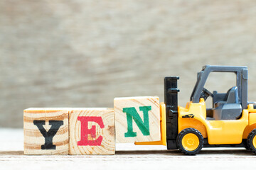 Wall Mural - Toy forklift hold letter block n to complete word yen on wood background