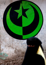 Muslim Woman In Niqab Passing By A Muslim Crescent And Star Sign In The Street, Lamu County, Lamu, Kenya