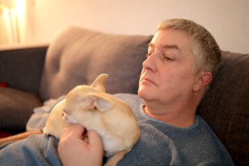 Caucasian man 47 years old hugging with love at his mini beige chihuahua dog