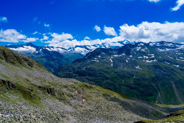 Wall Mural - Landscape mountain view peaks in snow and green hills, deep blue sky and huge white clouds background, Hohe Tauern Austrian Alps, Europe