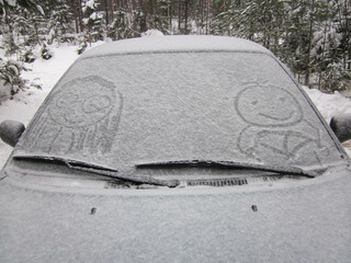 The image on the snow-covered windshield of the car of two persons - a driver and a passenger