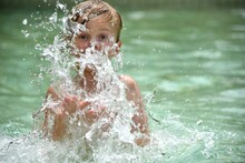 Portrait Of Shirtless Boy Splashing Water In Lake