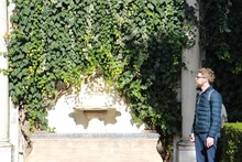 Man Standing Against Creeper Plants On Wall
