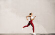 © Liubov Levytska - Healthy young woman running in morning. Fitness model exercising outdoors. Full length side view shot